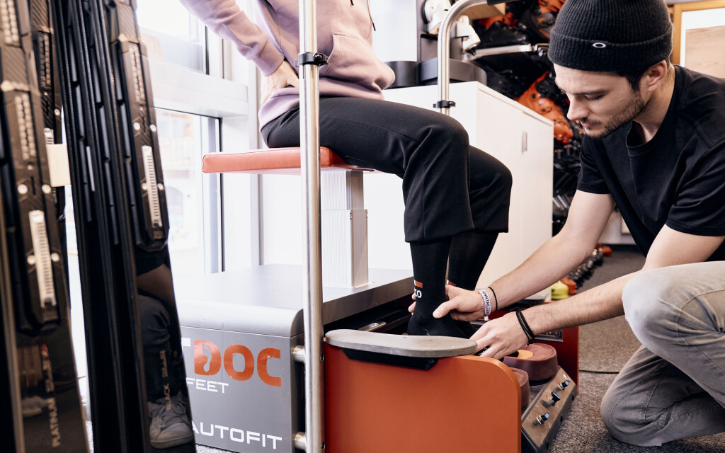 Ein Skishop-Techniker misst den Fuß eines Kunden mit einem DOC FEET AUTOFIT Gerät zur Skischuhanpassung.