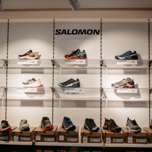 Salomon-Sportschuhe, auf Regalen in einem Einzelhandelsgeschäft ausgestellt, mit verschiedenen Lauf- und Trailschuhen.
