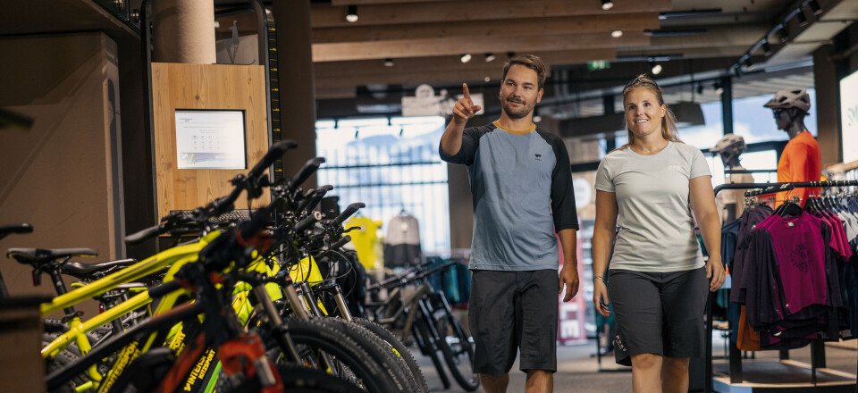 Ein Paar stöbert nach E-Bikes in einem geräumigen, modernen Fahrradgeschäft mit Kleiderständern.