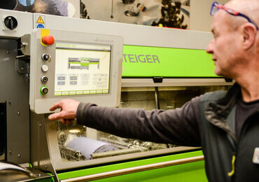 Bediener stellt eine STEIGER serviceproduktionsmaschine über ihr Touchscreen-Bedienfeld ein.