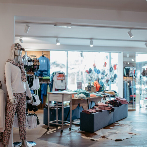 Geräumiger Innenraum eines Bekleidungsgeschäfts mit Schaufensterpuppen, die Sportbekleidung, Activewear und Freizeitkleidung präsentieren.