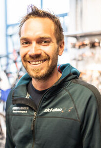 Lächelnder Mann mit Bart in einem Ski-Doo Hoodie, stehend in einem Outdoor-Sportgeschäft.